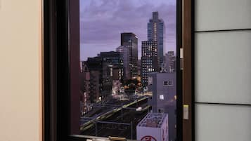 A cityscape view from a window, featuring tall buildings, a train track, and a bridge.