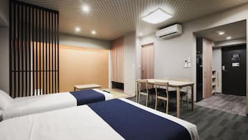 A hotel room with two beds, a desk, a chair, an air conditioning unit, and a door with a sign.