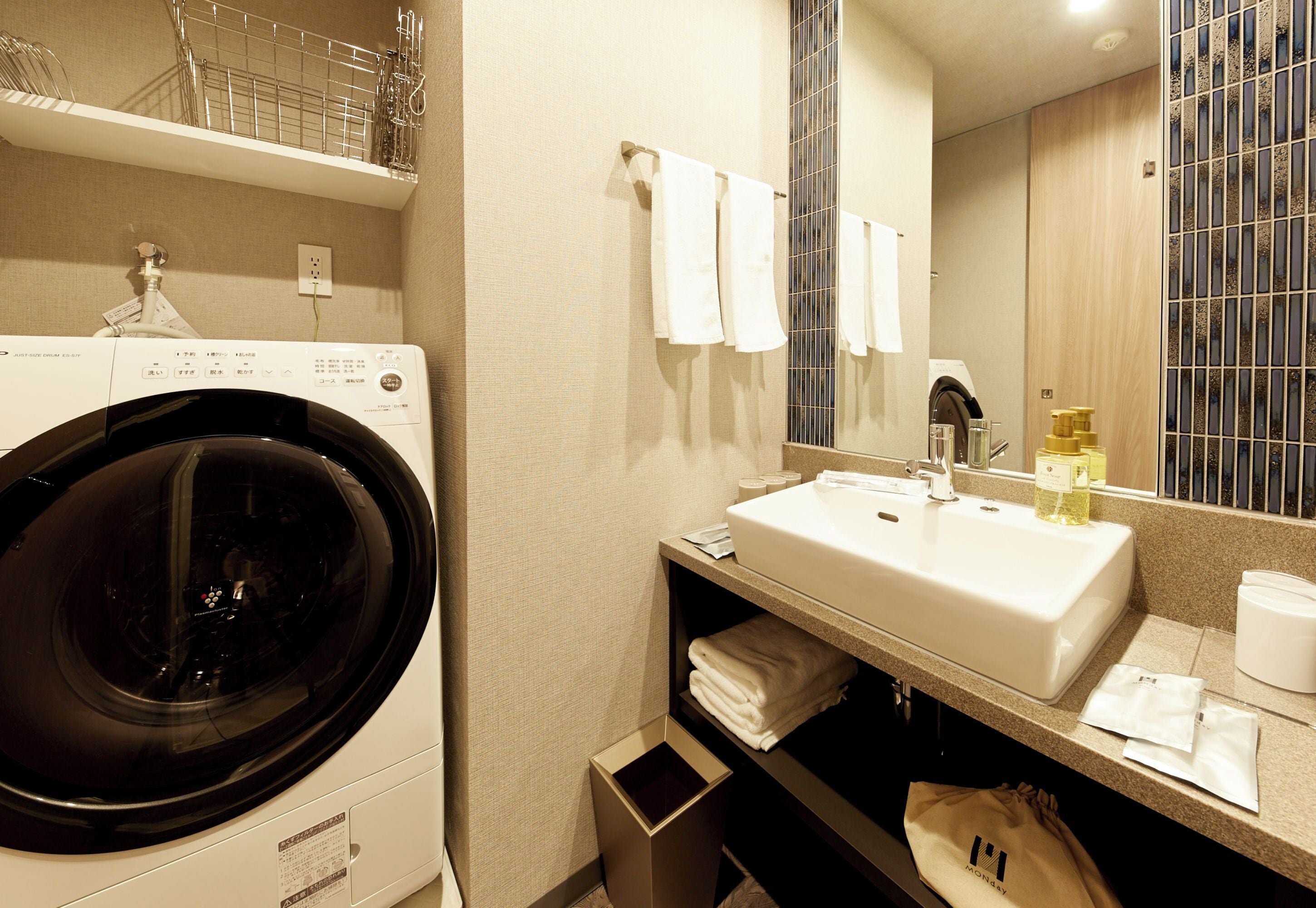 A hotel bathroom with a washing machine, sink, and towel rack.