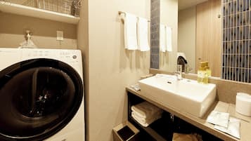 A hotel bathroom with a washing machine, sink, and towel rack.