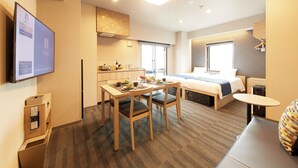 Une chambre d’hôtel avec un lit, un bureau, des chaises, une petite table, un téléviseur et une fenêtre.