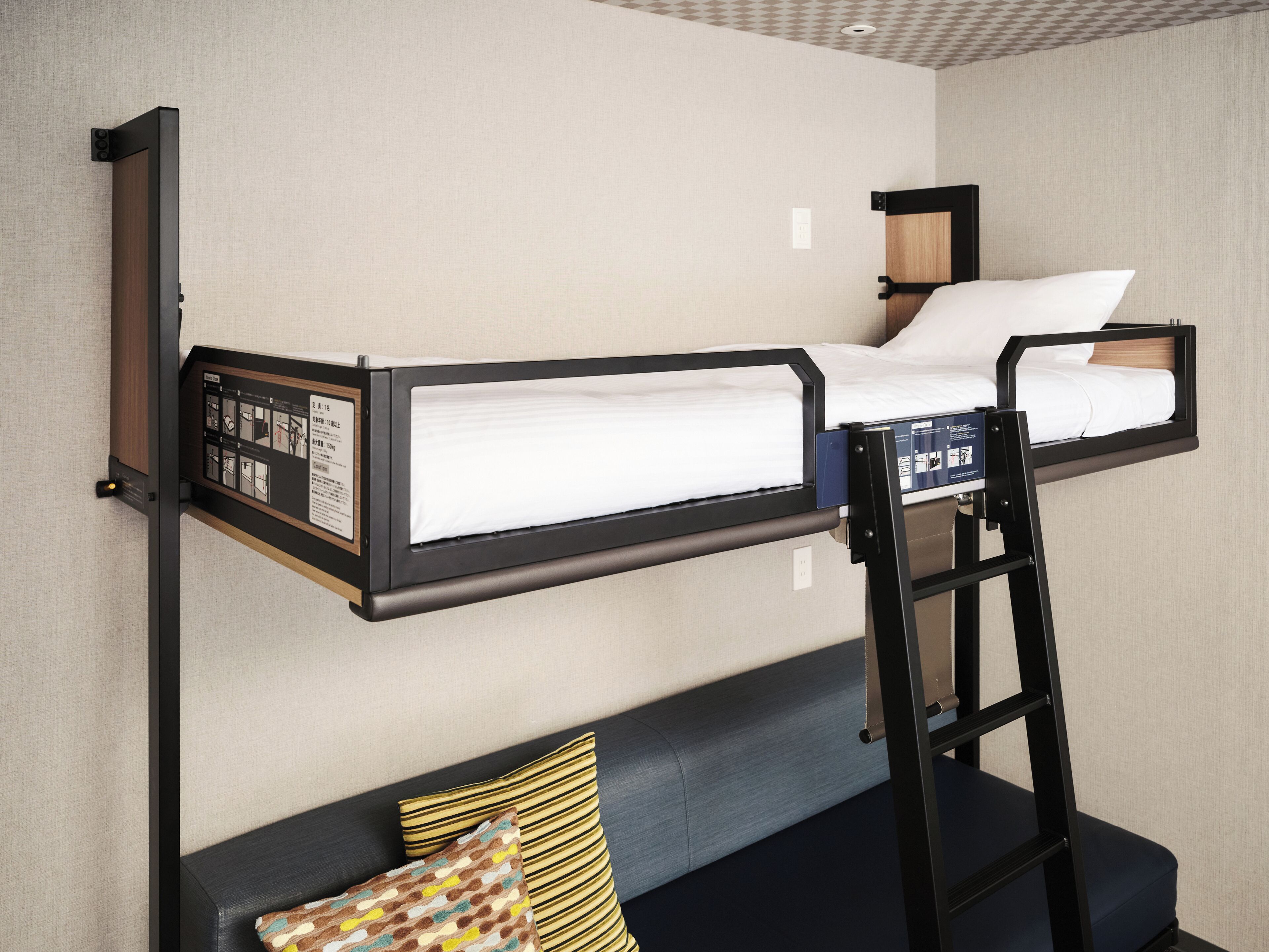 A bunk bed with a control panel, a desk, and a sofa with pillows.