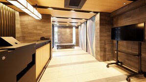 Un hall d’hôtel moderne avec un comptoir d’accueil, un téléviseur et un espace salon.