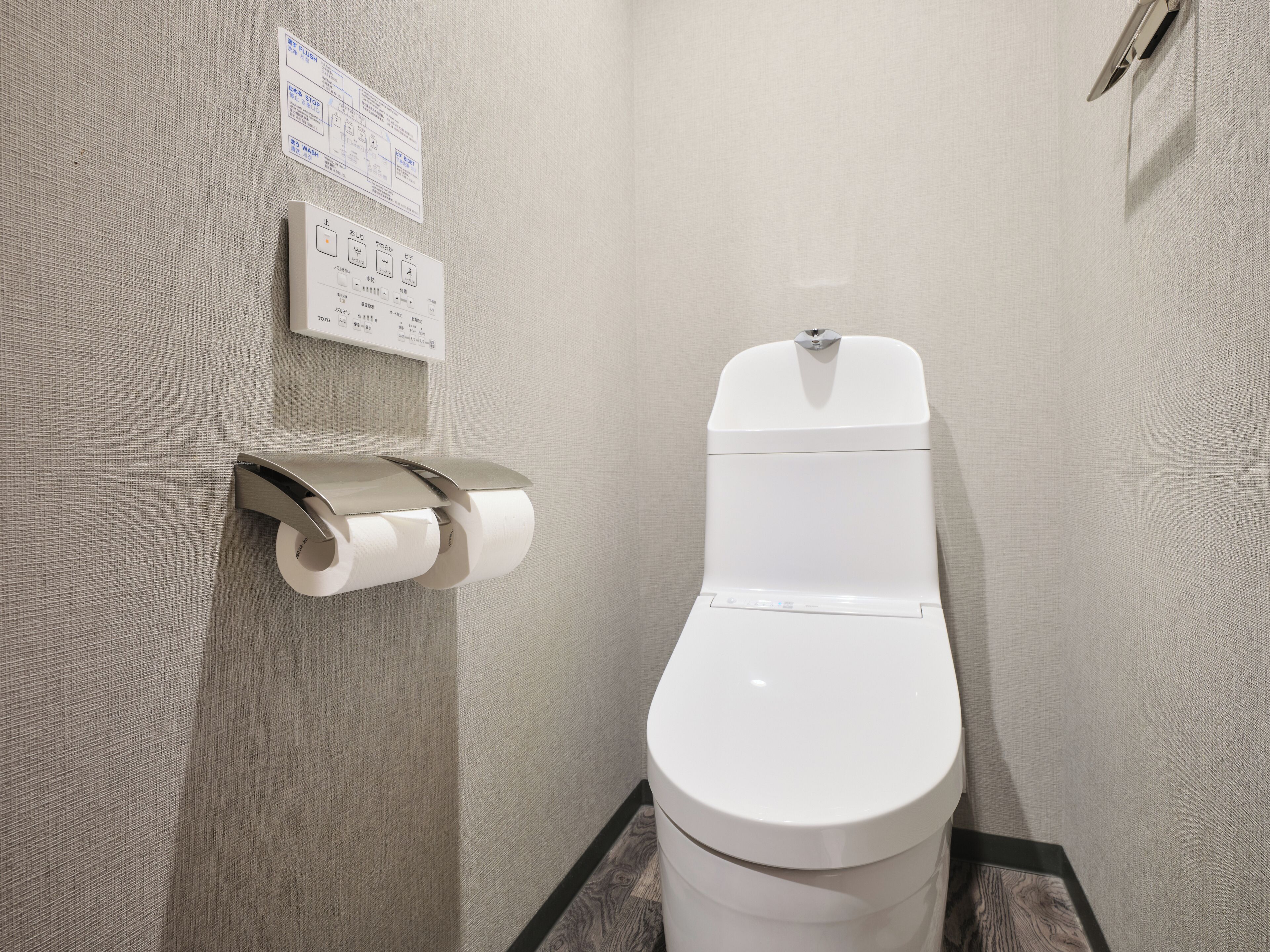 Une salle de bain moderne équipée de toilettes, d’un distributeur d’essuie-tout et d’un sèche-mains.