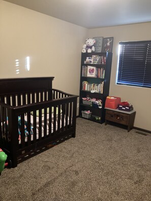 Cozy nursery with a crib, bookshelf, and nightstand, perfect for play and learning.