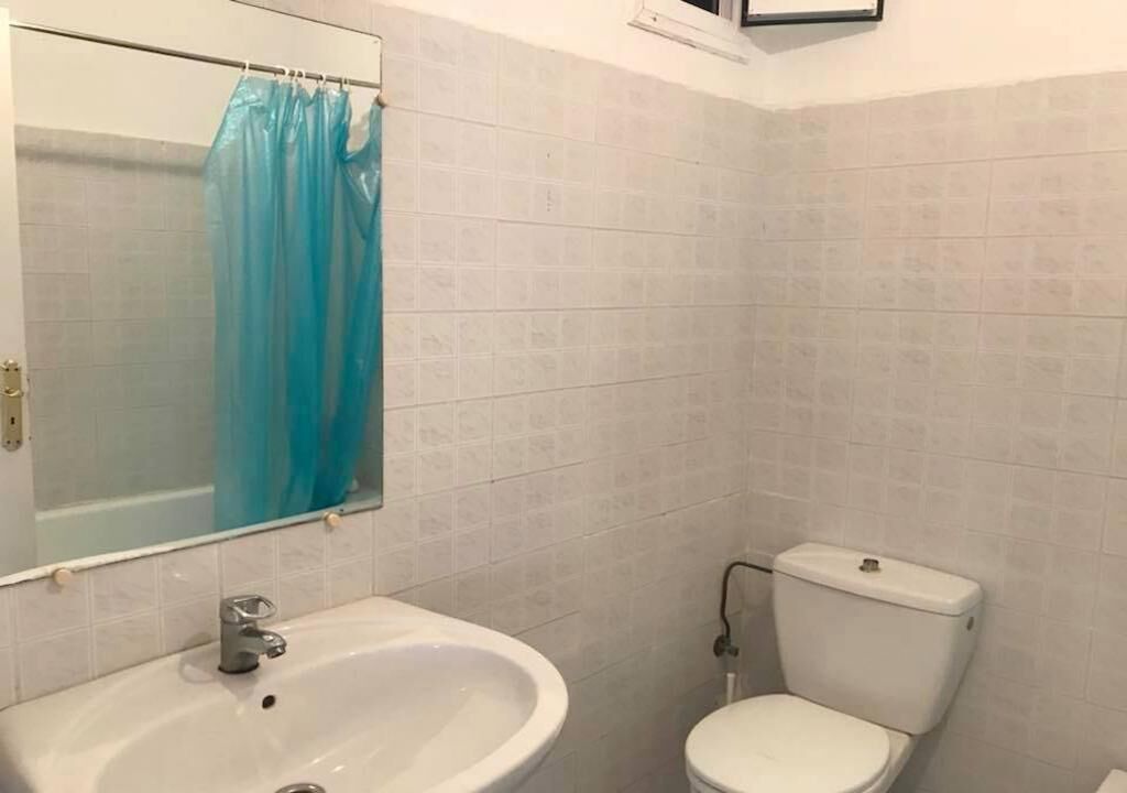 A bathroom with a white sink, a toilet, and a mirror with a blue shower curtain.