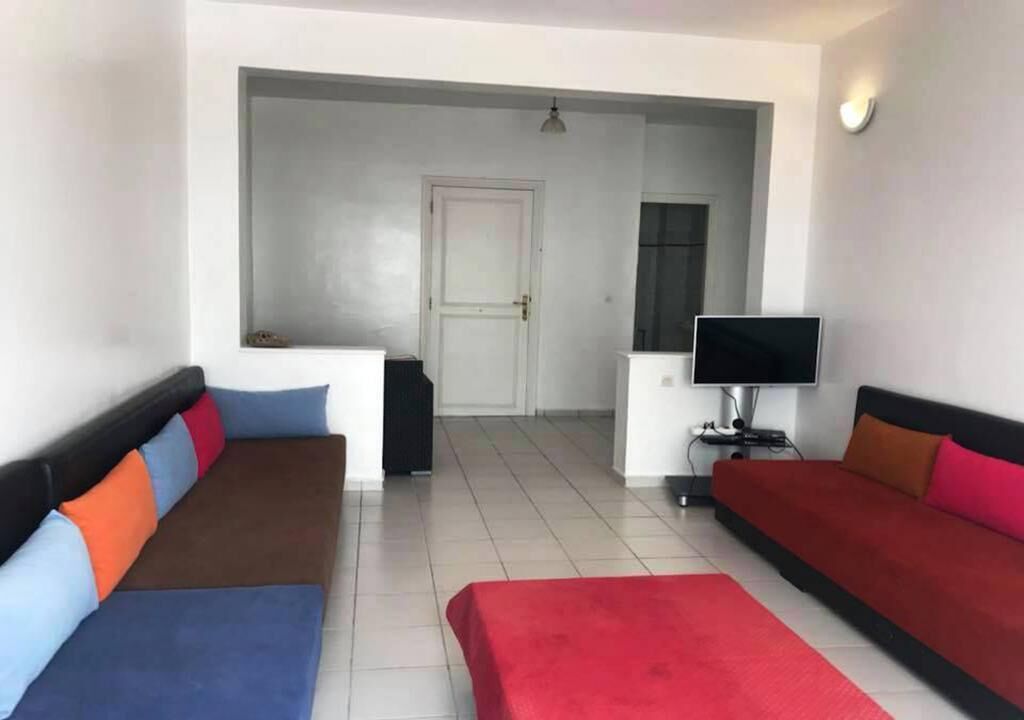 A room with two sofas, a television, and a door leading to another room.