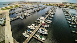 Un puerto deportivo con numerosas muelles y barcos, un puente al fondo y cielo despejado.