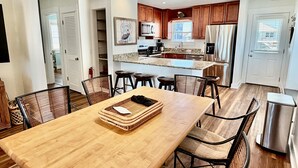 A modern kitchen with wooden cabinets, a central island, and a dining area with a wooden table and chairs.