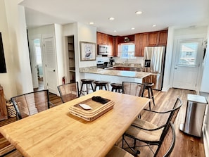 Une cuisine moderne avec des meubles en bois, un îlot central et un coin repas comprenant une table et des chaises en bois.
