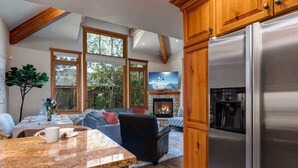 A kitchen with a stainless steel refrigerator, wooden cabinets, and a stone fireplace.