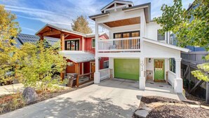 A two-story house with a green garage door, a balcony, and a covered front porch.