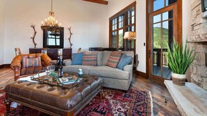 Una sala de estar amplia con un gran ventanal, chimenea y candelabro.