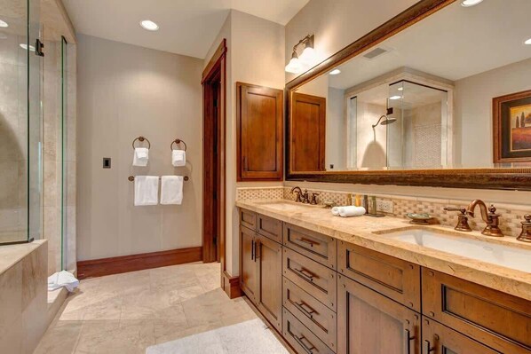 A bathroom with a large mirror, wooden cabinets, a double sink, and a glass shower enclosure. - Abode at Arrowleaf Overlook, ski-in/ski-out, hot tub, Deer Valley (Park City)