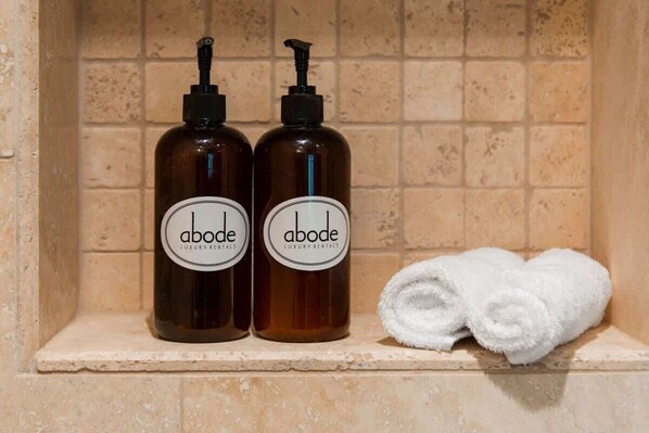 Two bottles of Abode Luxury Rentals toiletries and a rolled white towel on a shelf. - Abode at Arrowleaf Overlook, ski-in/ski-out, hot tub, Deer Valley (Park City)