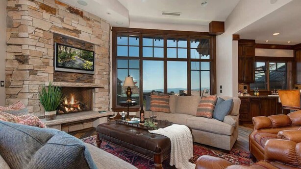 Una sala de estar con chimenea de piedra, un ventanal grande, sofás de cuero y una mesa de centro.