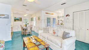 A spacious living area with a white sofa, a colorful table, and a ceiling fan.