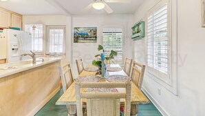 A dining area with a wooden table, wicker chairs, and a ceiling fan.