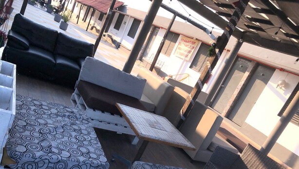 A covered outdoor seating area with white and grey cushioned benches and a patterned table. - Hotel Verasol (Veracruz)