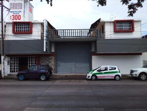 A building with a closed garage door, a balcony, and a sign indicating a price of $300. - Hotel Verasol (Veracruz)