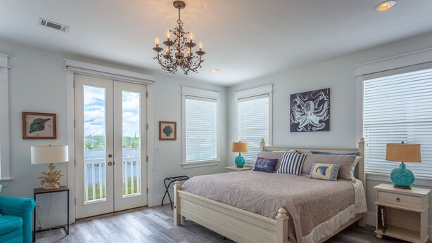 A bedroom with a bed, a chandelier, a window with blinds, and a door leading to a balcony. - Fish, Beach, Pool, Swim, Relax in Luxury Rent for the month only 5,900.00 (Carrabelle)