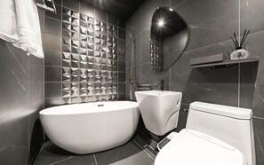 A modern bathroom with a freestanding bathtub, a pedestal sink, and a toilet. - Best Louis Hamilton Hotel Gijang (Busan)