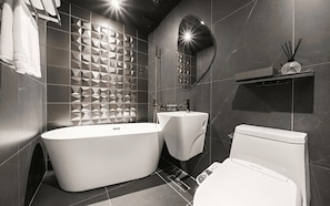 A modern bathroom with a freestanding bathtub, a wall-mounted sink, and a toilet. - Best Louis Hamilton Hotel Gijang (Busan)