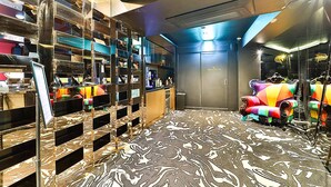 A modern hotel room with a marble-patterned floor, a large mirror, a vibrant armchair, and a minibar. - Best Louis Hamilton Hotel Gijang (Busan)