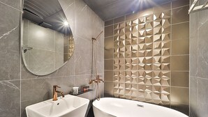 A modern bathroom with two sinks, a large bathtub, and a decorative wall panel. - Best Louis Hamilton Hotel Gijang (Busan)