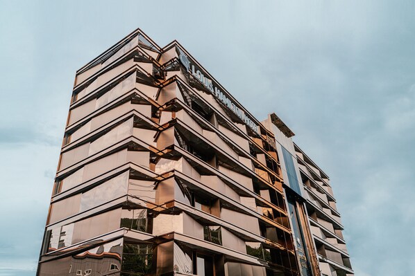 A multi-story hotel with a modern architectural design, featuring a prominent sign at the top. - Best Louis Hamilton Hotel Gijang (Busan)
