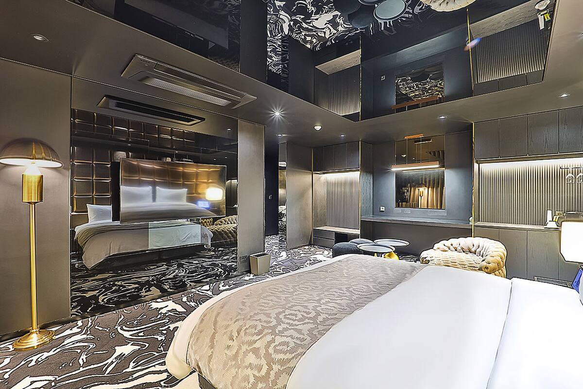 Una habitación de hotel moderna con una cama grande, un escritorio, una silla y una lámpara.