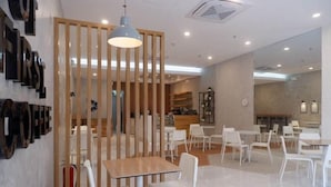 Una cafetería moderna con separadores de madera, sillas y mesas blancas.