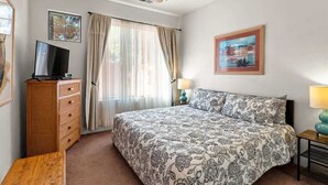 A bedroom with a bed, a television on a dresser, a ceiling fan, and a painting on the wall. - Light, Bright, Stylish Condo Nepenthe West Sedona (Sedona)