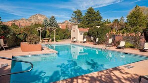 A swimming pool with lounge chairs and a pergola, surrounded by trees and mountains. - Light, Bright, Stylish Condo Nepenthe West Sedona (Sedona)
