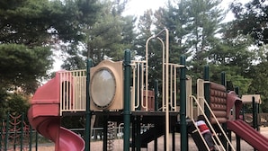 Un parque infantil con un tobogán, estructuras para escalar y un ventanal circular.