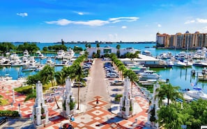 A marina with boats docked, a building with a sign, and a hotel in the background.