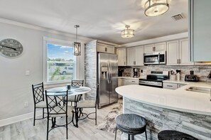 A modern kitchen with a central island, stainless steel appliances, and a dining area with a round table and chairs.