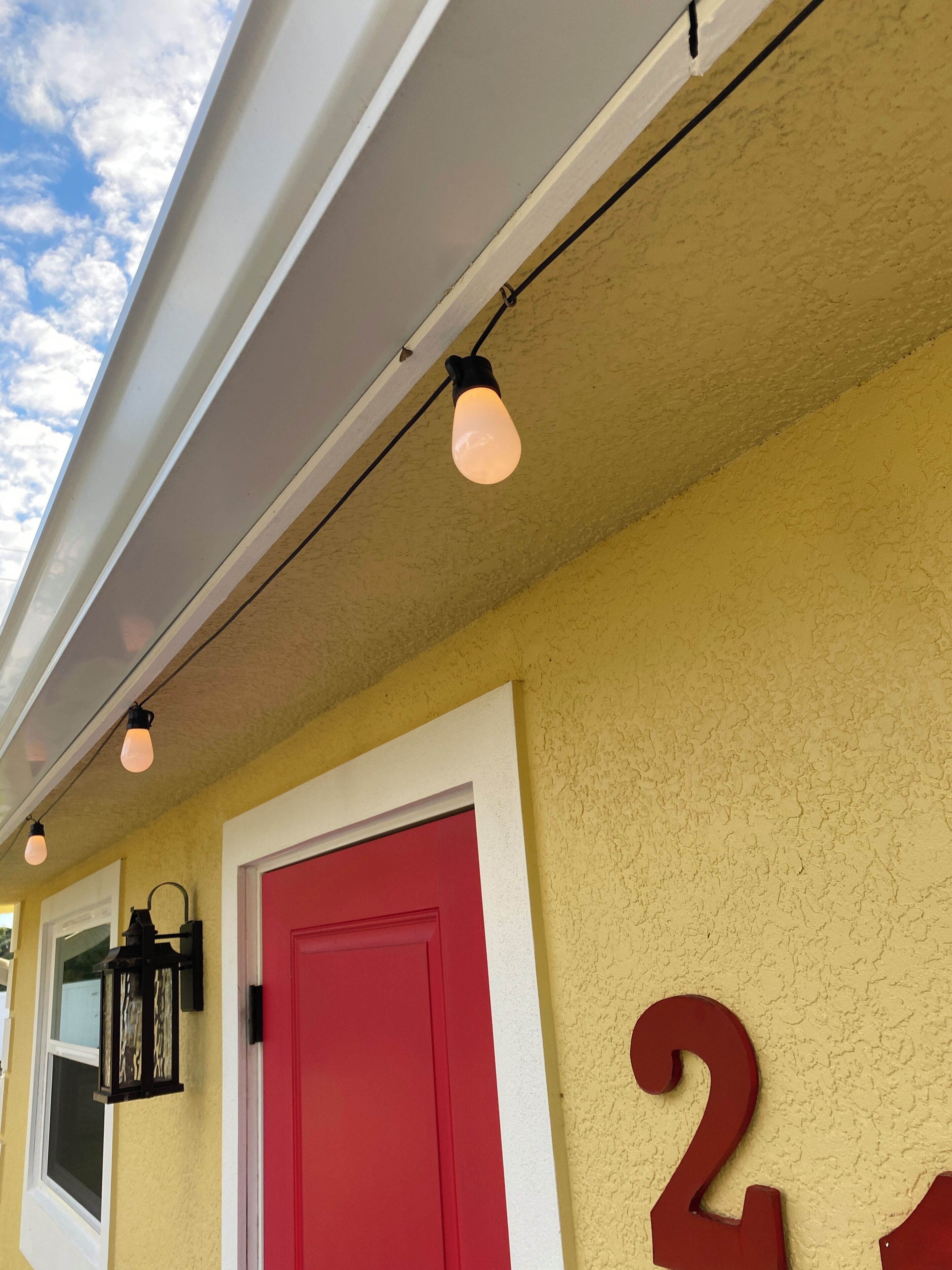 A building exterior with a red door, a number '2' sign, and a light fixture.