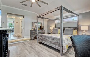 A four-poster bed with a wooden frame, a nightstand, a lamp, and a chair.