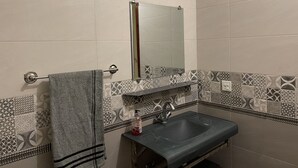 A bathroom with a sink, mirror, towel rack, and patterned tiles.