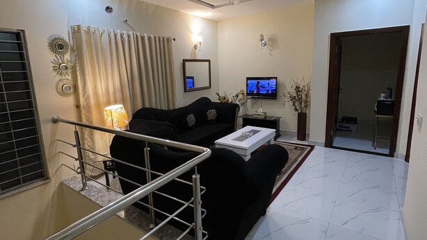 A modern living room with a black sofa, a TV, and a ceiling fan.