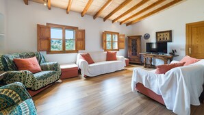 A spacious living area with wooden beams, two sofas, a television, and a cabinet. - Stunning Mountain Views and Pool – Villas Ca'n Tamany & Ca'n Baixo (soller)