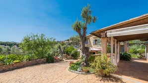 A courtyard with stone flooring, potted plants, a tree, and a building with a tiled roof. - Stunning Mountain Views and Pool – Villas Ca'n Tamany & Ca'n Baixo (soller)