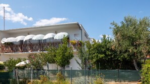 A two-story building with a balcony, white umbrellas, and a sign that reads "APARTMANNI". - A 2  apt near beach w patio, parking and grill (Stobrec)