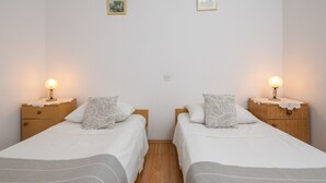 A room with two single beds, each with a nightstand and a lamp. There are two framed pictures on the wall. - A 2  apt near beach w patio, parking and grill (Stobrec)
