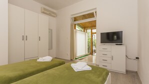 Ein Hotelzimmer mit zwei Betten, einem Fernseher, einem Kleiderschrank und einem durch eine offene Tür einsehbaren Badezimmer.