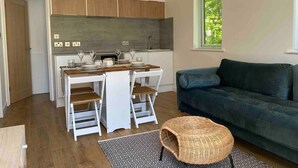 Une cuisine moderne avec des meubles blancs, une table à manger dressée avec des assiettes et des verres, et un canapé bleu dans l’espace salon.
