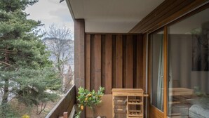 Un balcon avec un plancher en bois, un petit chariot en bois et un pot de fleurs contenant des fleurs jaunes.