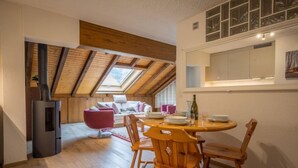 Une pièce chaleureuse avec un plafond en bois, une table à manger avec des chaises, un canapé et un petit réfrigérateur.