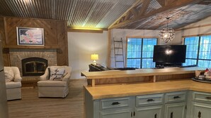 Een gezellige woonkamer met een open haard, een televisie en een eethoek met een houten aanrecht.